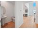 Hallway with wood floors leading to kitchen and view of a half bathroom with pedestal sink at 5719 Cattle Ranch Dr, St Cloud, FL 34771