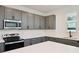 A well-equipped kitchen boasts gray cabinetry, stainless steel appliances, and white countertops at 5719 Cattle Ranch Dr, St Cloud, FL 34771