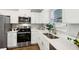 Well-appointed kitchen featuring stainless steel appliances, light counter tops, white cabinetry, and hardwood floors at 6551 Hemlock Rd, Ocala, FL 34472