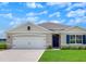 Charming one-story home features a two-car garage, inviting blue front door, and well-manicured lawn at 717 Squires Grove Dr, Winter Haven, FL 33880