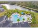 Aerial view of community pool with palm trees, lounge chairs, and lake backdrop at 3881 Sonoma Blvd, Kissimmee, FL 34741