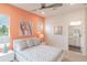 A serene bedroom with bright coral walls, a view of palm trees, and a bathroom in the background at 3881 Sonoma Blvd, Kissimmee, FL 34741