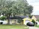 Lovely yellow home with an attached garage, enhanced by mature tree and front lawn landscaping at 1018 Martin Blvd, Orlando, FL 32825