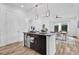 Bright kitchen featuring an island with a sink, dark cabinets, stainless steel appliances, and light-colored flooring at 10257 Henbury St, Orlando, FL 32832