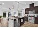 Open-concept kitchen with dark cabinets, a stainless steel dishwasher, a breakfast bar, and views to the dining area at 10257 Henbury St, Orlando, FL 32832