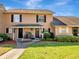 Inviting two-story townhouse featuring a well-manicured lawn, dark shutters, and a covered entryway at 1174 Villa Ln # 115, Apopka, FL 32712