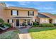 Charming townhouse exterior with lush landscaping, black shutters, and a quaint front yard seating area at 1174 Villa Ln # 115, Apopka, FL 32712