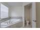 Modern bathroom featuring a corner bathtub, tile accents, and an enclosed toilet at 11810 Imaginary Way, Orlando, FL 32832