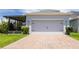 Two-car garage featuring a brick-paved driveway, manicured landscaping, and convenient screened-in porch access at 11810 Imaginary Way, Orlando, FL 32832