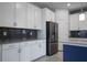 Close-up of a kitchen featuring white cabinetry, a stainless steel refrigerator, and a dark backsplash at 11810 Imaginary Way, Orlando, FL 32832