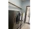 Modern laundry room with front-load washer and dryer and a wire shelf at 11810 Imaginary Way, Orlando, FL 32832