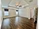 Spacious main bedroom featuring tray ceiling, ceiling fan, and rich hardwood flooring at 11810 Imaginary Way, Orlando, FL 32832
