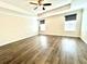 Bright main bedroom with hardwood floors, a fan, and two sunny windows at 11810 Imaginary Way, Orlando, FL 32832