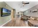 Open-concept living room with wood-look tile flooring, a large sofa, and a view of the kitchen at 11980 Sands Cv, Orlando, FL 32828