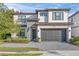 Two story home featuring a paved driveway, two car garage, stone accents, and manicured landscaping at 1205 Butterfly Orchid Rd, Davenport, FL 33837