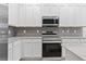 Modern kitchen features white cabinets, gray backsplash, and stainless steel appliances at 1205 Butterfly Orchid Rd, Davenport, FL 33837