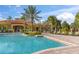 Resort-style community pool with a spacious deck, lounge chairs, tropical landscaping, and a clubhouse in the background at 1205 Butterfly Orchid Rd, Davenport, FL 33837