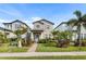 Charming two-story home featuring a manicured lawn, walkway lighting, and lush tropical landscaping at 17087 Wynford Ln, Winter Garden, FL 34787