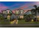 Charming two-story home featuring a manicured lawn, walkway lighting, and lush tropical landscaping at 17087 Wynford Ln, Winter Garden, FL 34787