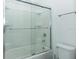Bathroom featuring tub with clear glass door and white tile surround and toilet at 2145 Fleming Mist Pl, Kissimmee, FL 34747