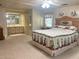 Spacious main bedroom with en-suite bathroom features a decorative headboard, floral accents, and neutral carpet at 223 Pinewood Dr, Eustis, FL 32726