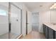 Tiled shower with glass door is open to the bathroom with grey cabinets and a view to the Primary bedroom at 2354 Broadbrook Dr, St Cloud, FL 34771