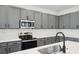 Modern kitchen featuring stainless steel appliances, gray cabinets, white backsplash, and a quartz countertop with a sink at 2354 Broadbrook Dr, St Cloud, FL 34771