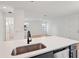 A spacious kitchen features stainless steel appliances, grey cabinets, and a quartz countertop island with view to other rooms at 2354 Broadbrook Dr, St Cloud, FL 34771