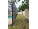 A narrow grass strip borders the screened-in pool, offering a glimpse of the property's fenced perimeter at 236 Bay Head Dr, Kissimmee, FL 34743
