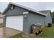 The house exterior showcasing an attached garage with a white door, and two garbage bins at 236 Bay Head Dr, Kissimmee, FL 34743