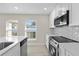 Updated kitchen features stainless steel appliances, quartz countertops, white cabinetry, tile backsplash, and recessed lighting at 2418 Whitehall Cir, Winter Park, FL 32792