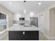 Bright kitchen showcasing white cabinets, a stainless steel refrigerator, and an island with a quartz countertop and stylish light fixture at 2418 Whitehall Cir, Winter Park, FL 32792