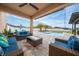 Backyard features covered patio with lounge furniture, pool, and palm trees at 2424 Varenna Loop, Kissimmee, FL 34741