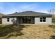 The backyard has a gray house with a sliding glass door, windows and a flat, grassy lot at 30369 Apricot Ave, Eustis, FL 32736