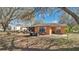 View of the back of the home and backyard, with ample space, trees, and a trailer at 37149 Sandy Ln, Grand Island, FL 32735