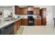 Functional kitchen featuring wooden cabinets, black appliances, and tile flooring at 3823 Ryegrass St, Clermont, FL 34714