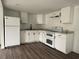 Bright kitchen featuring white cabinetry, modern appliances, dark hardware, and stylish wood-look flooring at 3931 Avenue R Nw, Winter Haven, FL 33881