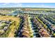 Expansive aerial view of a community with numerous houses and a scenic lake under a bright, sunny sky at 5260 Oakbourne Ave, Davenport, FL 33837