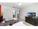 Bright bedroom featuring closet, en suite bathroom, and dark wood dresser with TV on top at 5260 Oakbourne Ave, Davenport, FL 33837