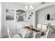 Elegant dining area with a glass table, white chairs, modern lighting and a pass-through to an additional room at 5260 Oakbourne Ave, Davenport, FL 33837