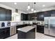 Modern kitchen featuring black cabinets, stainless steel appliances, granite countertops and an eat-in island at 5260 Oakbourne Ave, Davenport, FL 33837