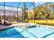 Close-up of a screened-in pool and spa area with mature landscaping at 5260 Oakbourne Ave, Davenport, FL 33837
