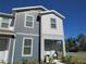 Two-story townhome with light gray and dark gray siding, trimmed landscaping, and a covered porch area at 6147 Arbor Watch Loop, Orlando, FL 32829