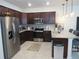 Well-lit kitchen with stainless appliances, dark wood cabinets, tile backsplash, and an island breakfast bar at 6147 Arbor Watch Loop, Orlando, FL 32829