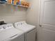 Functional laundry room with modern white appliances, and wire shelving for storage at 6147 Arbor Watch Loop, Orlando, FL 32829