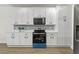Updated kitchen with white cabinetry, a black range and microwave, and modern backsplash at 6881 Piazza St, Orlando, FL 32819