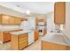 Open kitchen with an island, oak cabinets, and white appliances at 9526 Water Fern Cir, Clermont, FL 34711