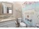 Bright bathroom featuring a granite countertop, white vanity, toilet, and decorative mermaid-themed shower curtain at 10732 Petrillo Way, Winter Garden, FL 34787