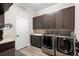 Well-equipped laundry room with front loading washer and dryer, granite counters, and dark wood cabinetry at 10732 Petrillo Way, Winter Garden, FL 34787