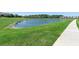Scenic view of a pond with lush green grass and a sidewalk at 10732 Petrillo Way, Winter Garden, FL 34787